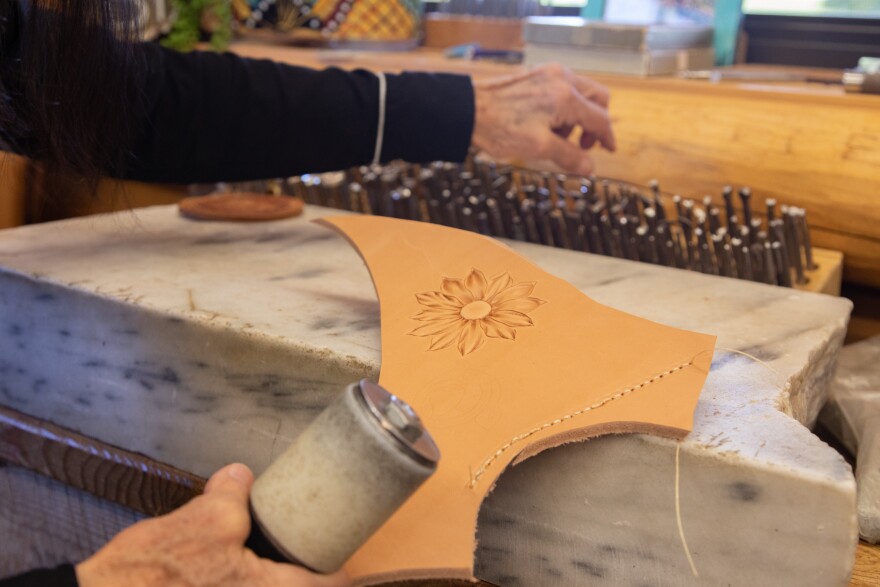 An engraved flower on a tan piece of leather laying on a marble slab.