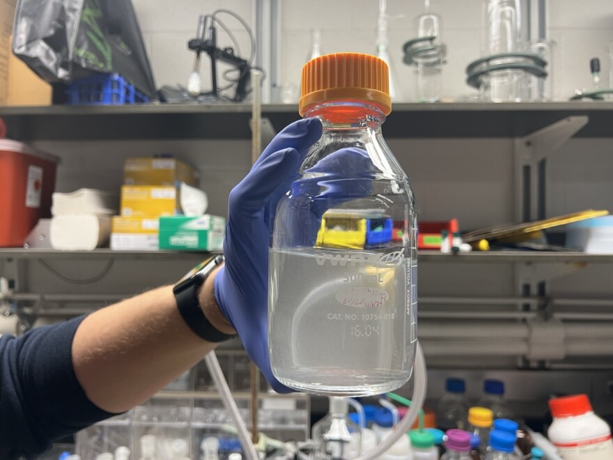 Henry Thurber, a student at the University of Michigan, holds a solution tainted with microplastics before passing it through a filter. (credit: Michael Livingston / Points North)