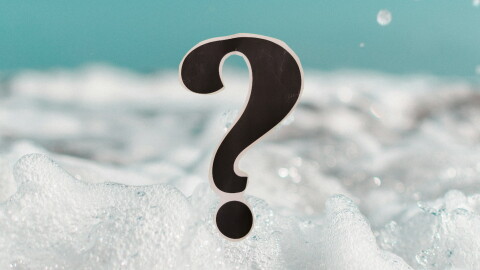 Close-up of bubbles in a bubble bath; a question mark in the foreground