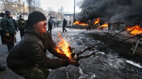 A protester prepares to hurl a Molotov cocktail at police in downtown Kiev, Ukraine. Ukrainian opposition leaders issued an ultimatum to the president: call for an early election or face attack.