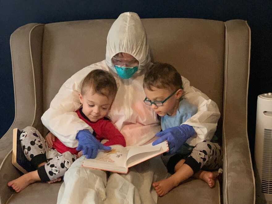 Dr. Lauren Jenkins reads to her twin sons, Pierce and Ashton, while wearing her "hazmat" suit. Because lung cancer has compromised her husband's immune system, Jenkins moved out of her home and visited in the suit as a precaution.