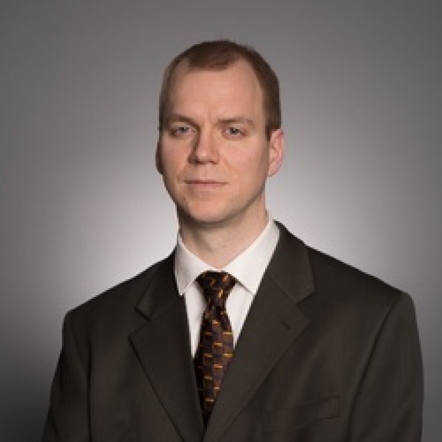 Headshot of a man in a dark suit and tie