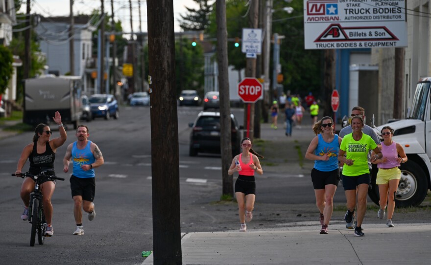Georgina Prosachik rides her bike alongside runners during a training run.
