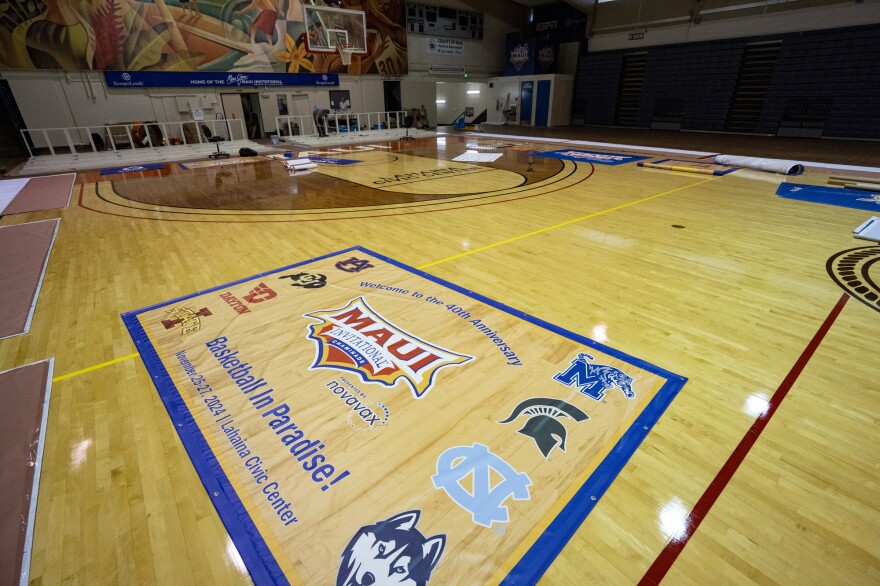 Workers set up banners and signs at Lahaina Civic Center, the venue for the Maui Invitational, Monday, Nov. 18, 2024, in Lahaina, Hawaii. The Maui Invitational is back in Lahaina, where eight of the NCAA's top men's basketball teams will compete in a three-day tournament. (AP Photo/Mengshin Lin)