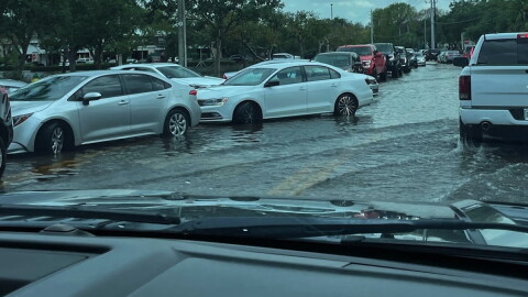 cars try to get through a flooded road