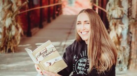 Author Cecilia Garcia, seated on steps holding her book