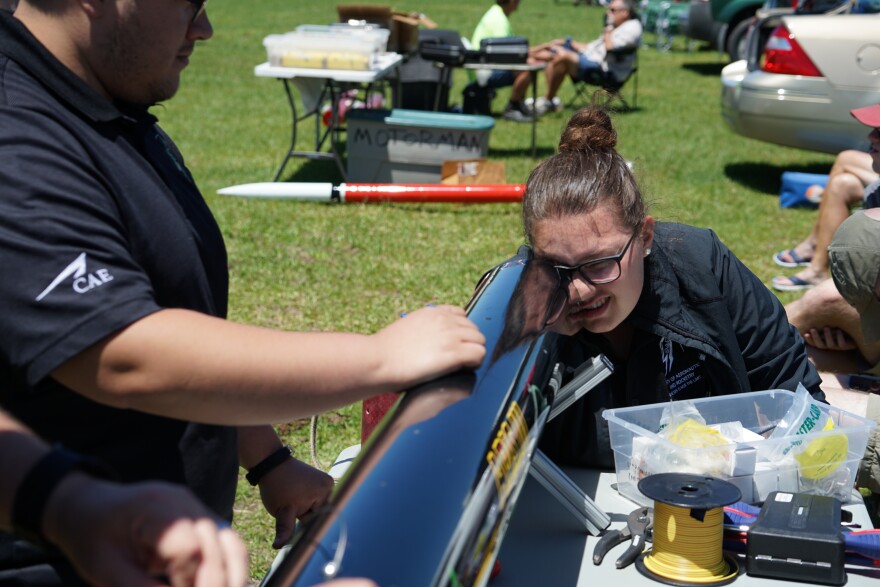 Student looking inside a rocket with one eye.