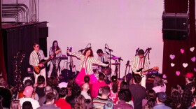 A crowd of people watch the band Ramona and the Sometimes perform at xBk Live in coordinating striped shirts.