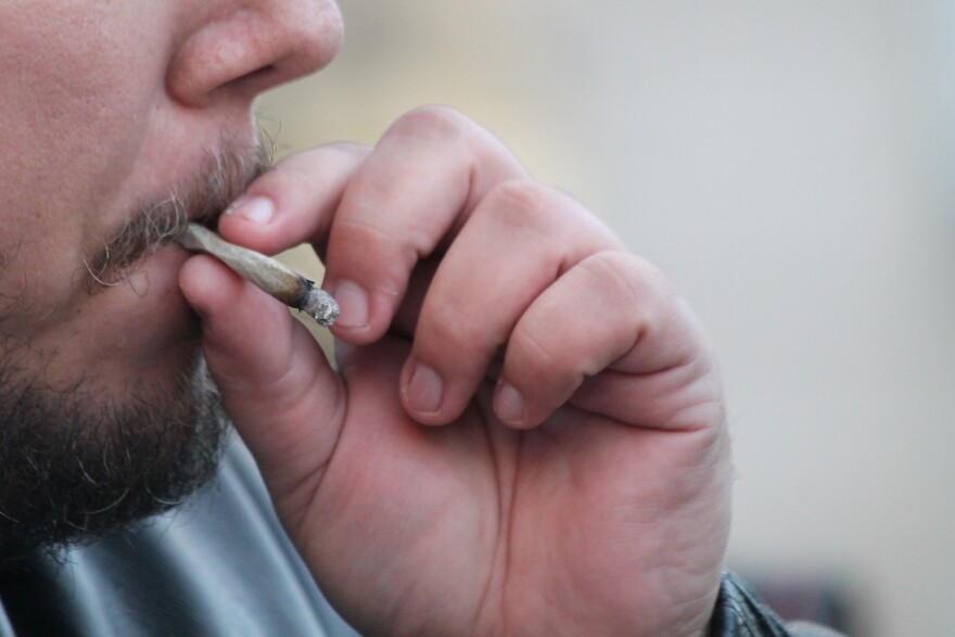 A man smoking a marijuana joint. 