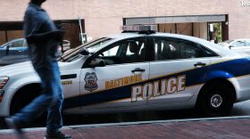 A person walks past a police car in Baltimore, Maryland.