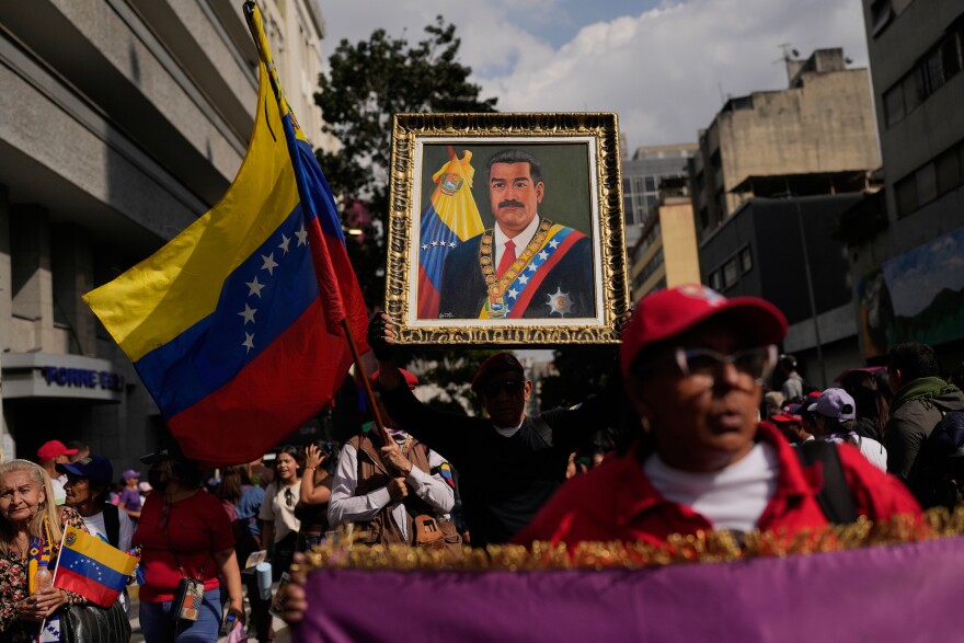 A government supporter holds an image of President Nicolas Maduro during a women's march to demand his return in Caracas, Venezuela, Tuesday, Jan. 6, 2026, three days after U.S. forces captured him and his wife. (AP Photo/Matias Delacroix)