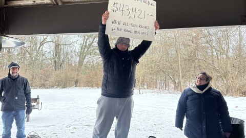 Jason Samuel holds up a poster board showing the $43,421 raised at the Maple City Ice Bowl, a national-record total for a single event.