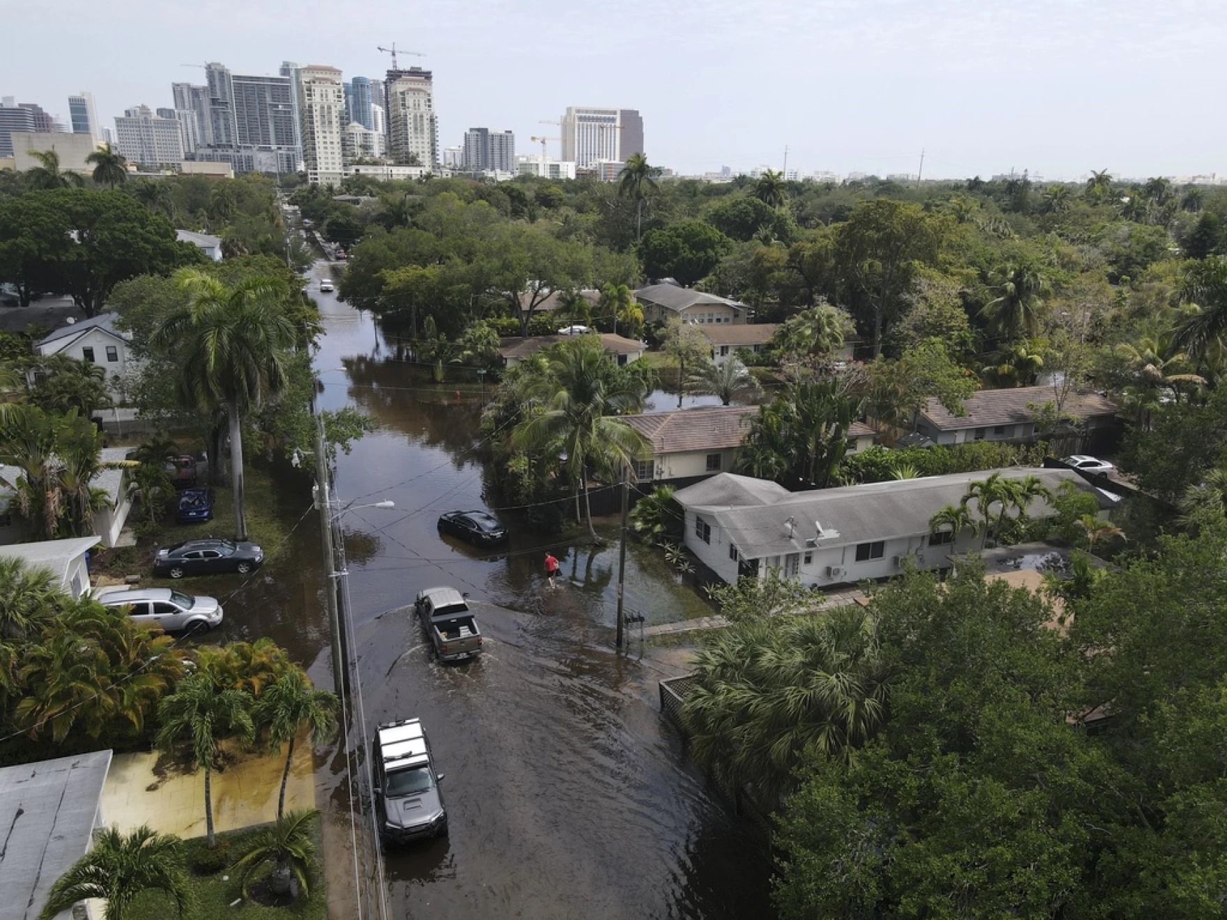 Trucks and a resident on foot make their way through receding floodwaters in the Sailboat Bend neighborhood of Fort Lauderdale, April 13, 2023. Over 25 inches of rain fell in South Florida since Monday, causing widespread flooding.