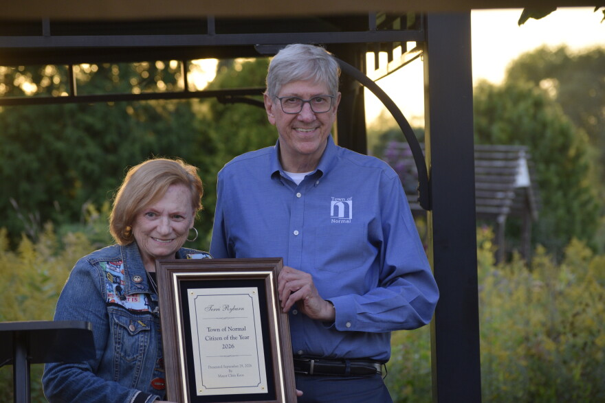 A man and woman stand for a picture holding a plaque. 