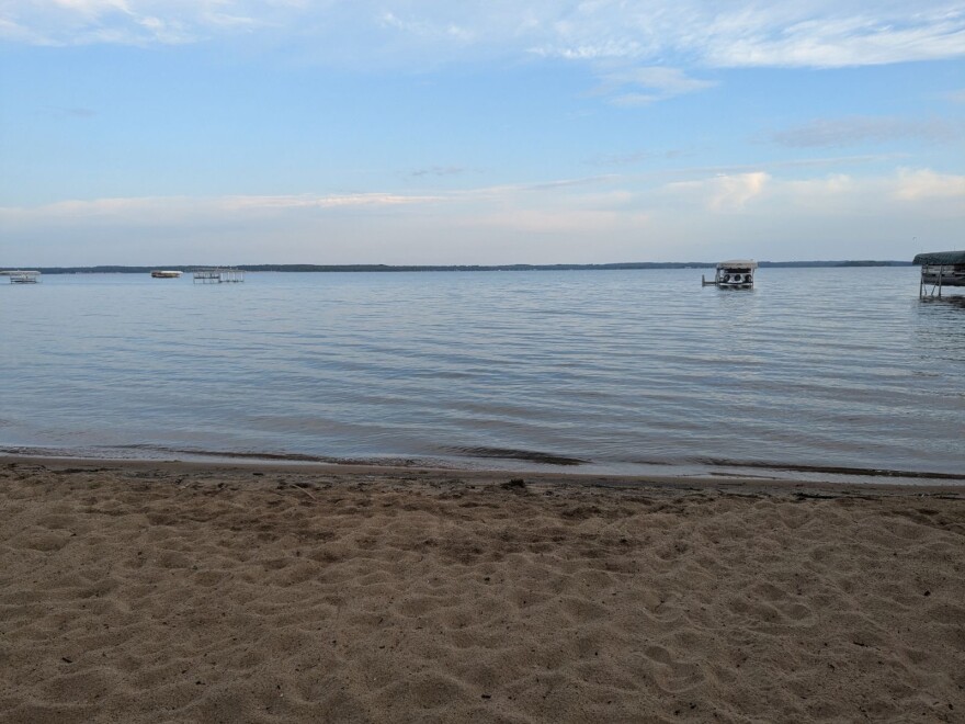A sandy beach and bright blue water of a lake in northern Minnesota.