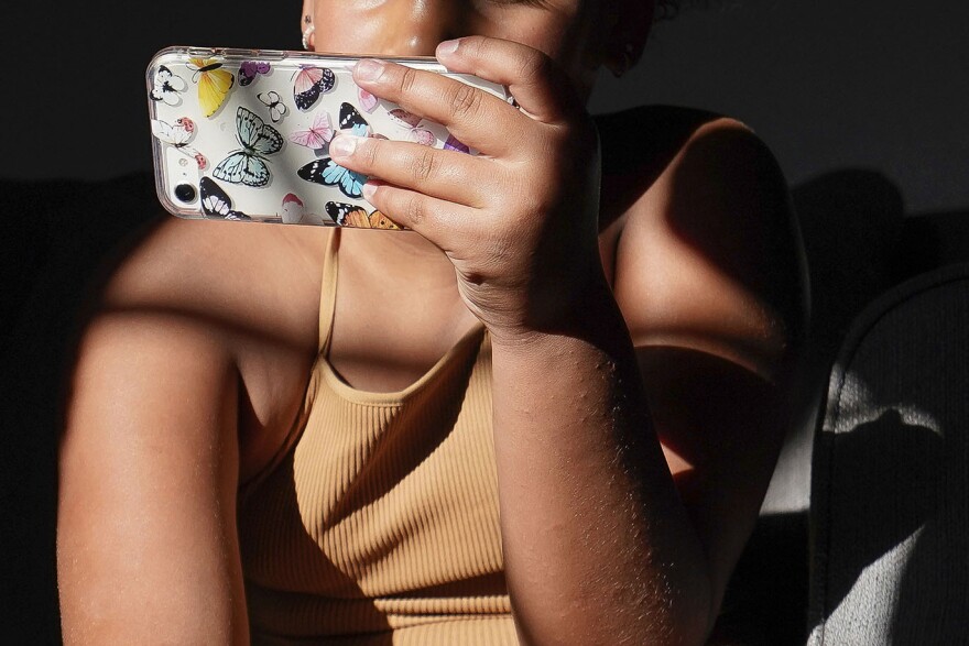 A girl uses her smartphone at home in Arizona on Friday, June 16, 2023.