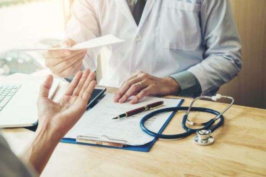 Doctor or physician writing diagnosis and giving a medical prescription to female Patient (IStockphoto/IStockphoto)