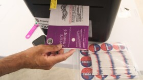 Los Angeles County election worker Richard Arias, deposits a ballot envelope after checking for written name and signature, as people vote in person on California's Prop 50 election at the Los Angeles County Registrar-Recorder's office Oct. 29, 2025.