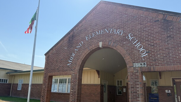 A brick archway in front of a school reads: Midland Elementary