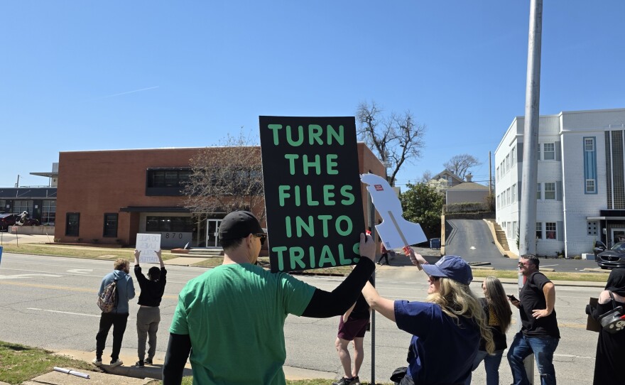A protester holds up a sign reading "TURN THE FILES INTO TRIAL," referencing files related to the late sex offender Jeffrey Epstein, at Tulsa's third "No Kings" rally on March 28, 2026.