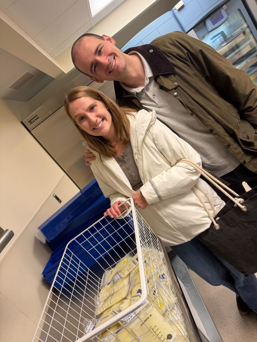 Lindsey and Eric Huebner stand next to a basket of Lindsey's frozen breast milk