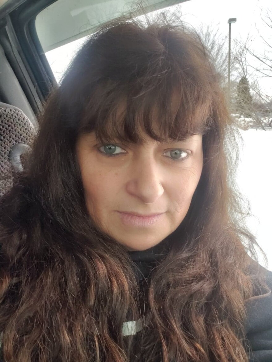 A white woman with brown hair sits in a car