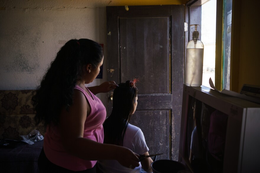 Cinthia styles a friend's hair at Pan de Vida Migrant Shelter in Ciudad Juarez on Sept., 6, 2020.
