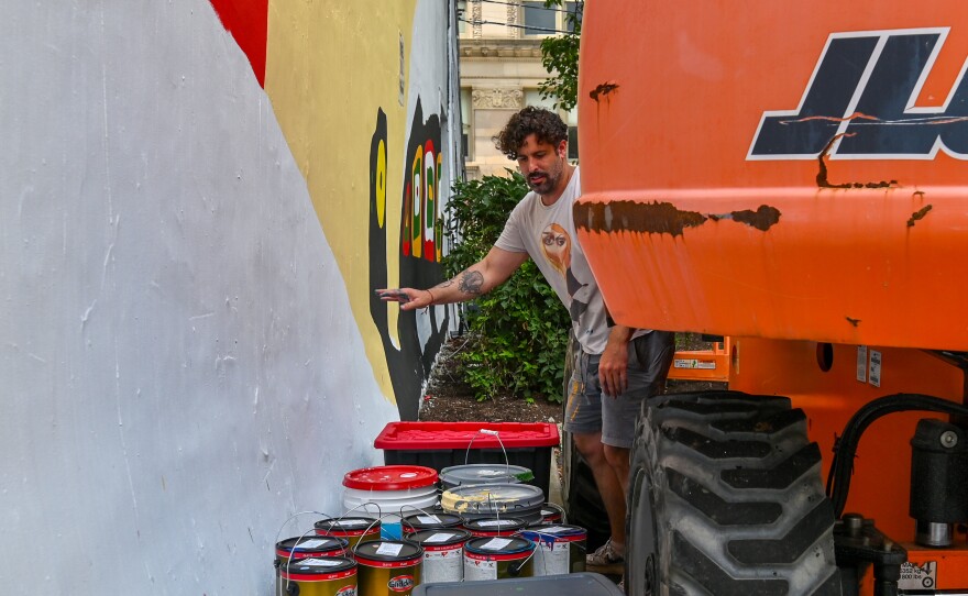Artist Belin prepares paint for a new mural in Scranton.