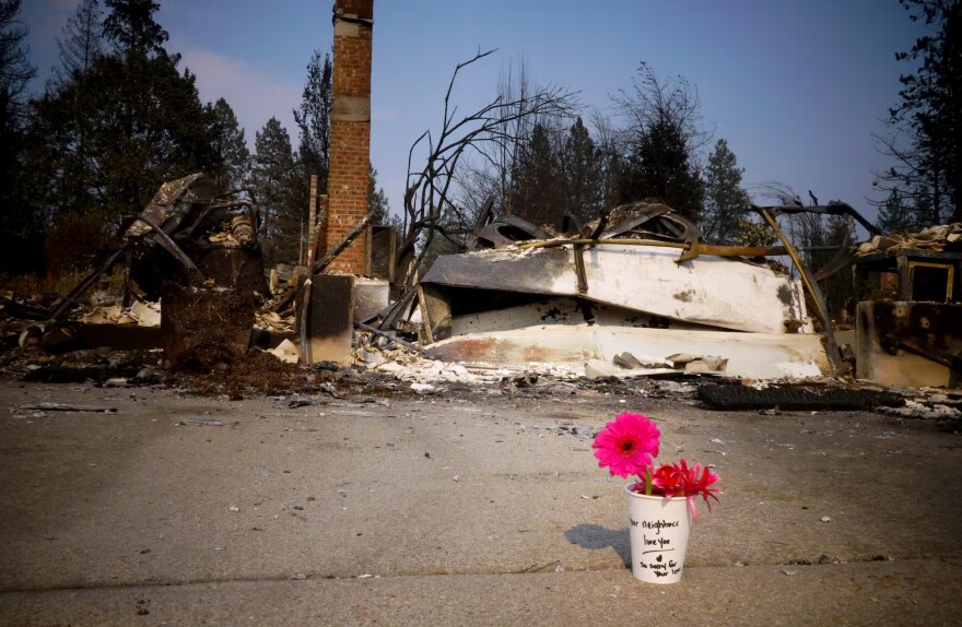 Paper cups with flowers are placed in front of a burned home in Spokane, Wash. on Aug. 6, 2026. People placed the flowers to express condolences for homes destroyed in the Old Trail Fire.