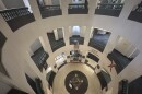 A view looking down through the open rotunda of the Leon County Courthouse in Tallahassee. On the ground floor, the county seal is embedded in the tile floor beneath an American flag hanging from the second level.