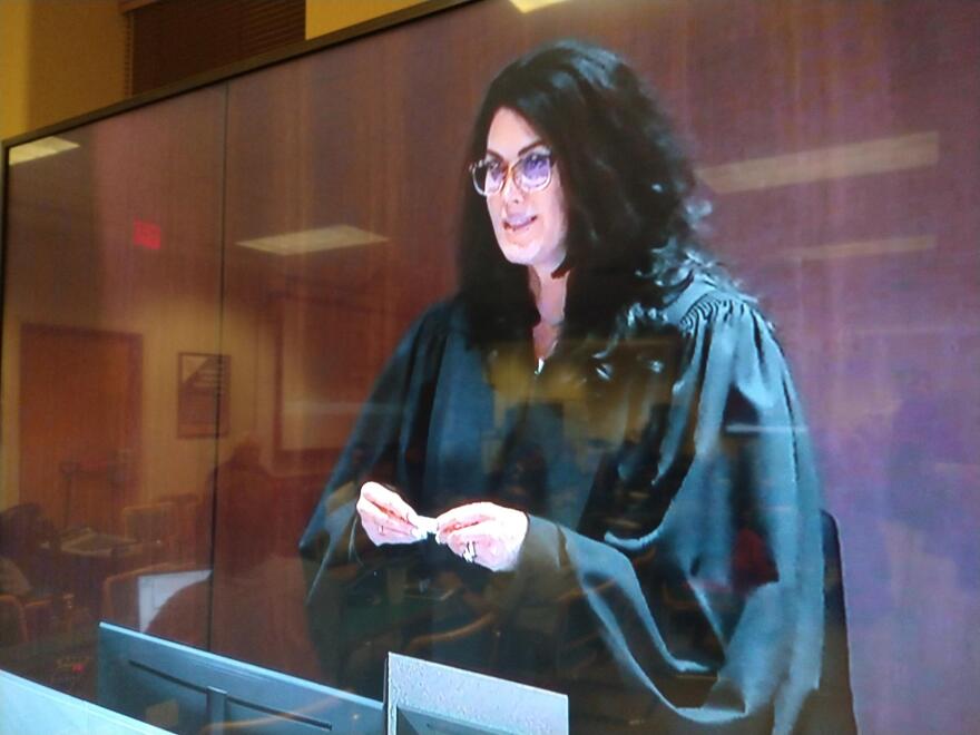 Trial judge Jennifer Dorow chooses juror numbers from a tumbler, to determine which three of the fifteen jurors who have been hearing the parade deaths case, will now serve as alternates, during deliberations.