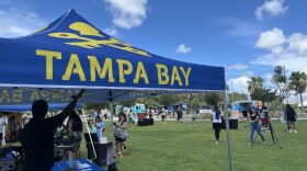 A canopy with the team's logo and colors on it, with a crowd of people enjoying the festivities in the background.