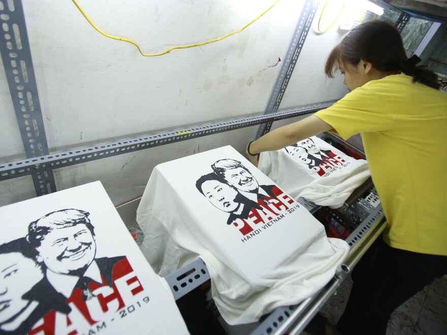 A worker removes T-shirts printed with portraits of President Trump and North Korean leader Kim Jong Un at a custom T-shirt shop in Hanoi last week.