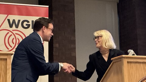 A man and a woman shake hands at a podium 