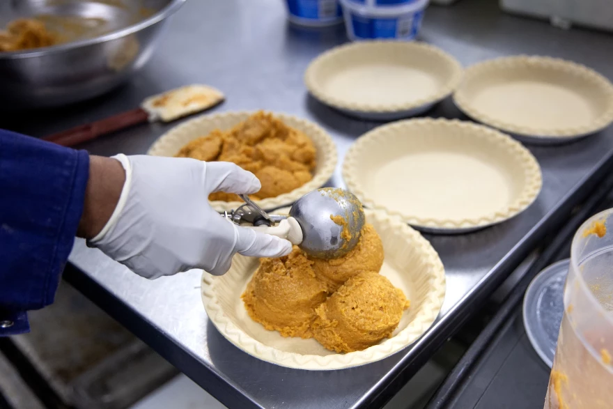 Pastry Chef Carla Jones scoops globs of sweet potato pie mixture into shells of pie dough on Nov. 15, 2023 at Ol' Henry's Restaurant in Berkeley, Missouri.