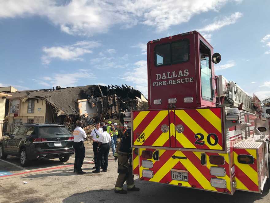 A photo of a fire truck in front of a partially collapsed building.