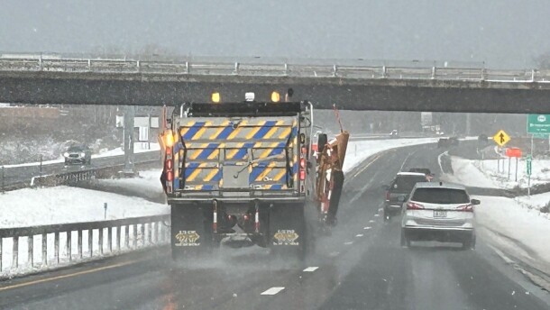 A snowplow and several cars on a highway near Syracuse with snow on the ground