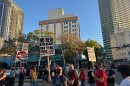 people holding protest signs, some wearing masks, gathered on the intersection of 3rd street and first avenue of downtown St. Petersburg