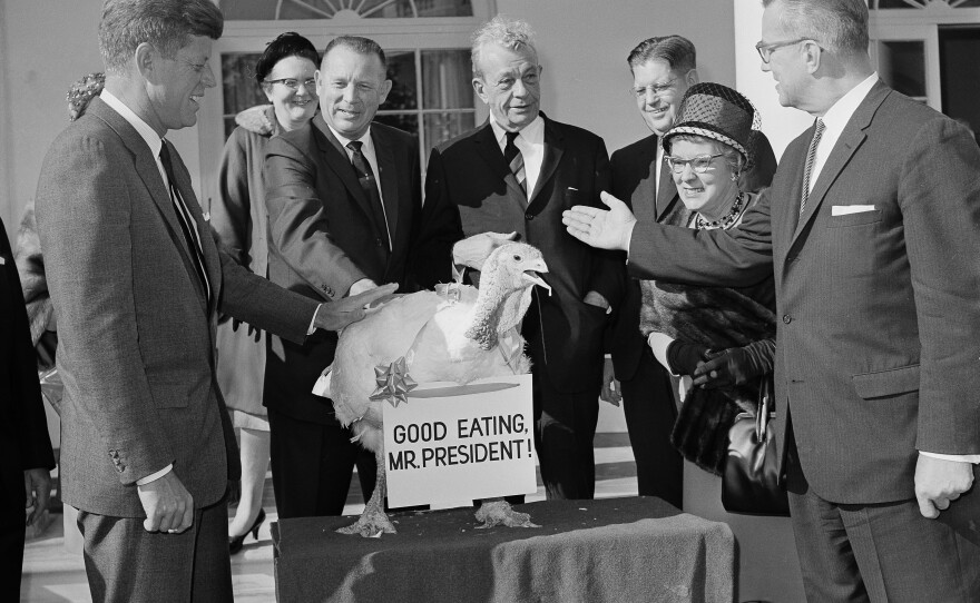 President John F. Kennedy reaches out to touch a turkey presented to him at the White House from the turkey industry.