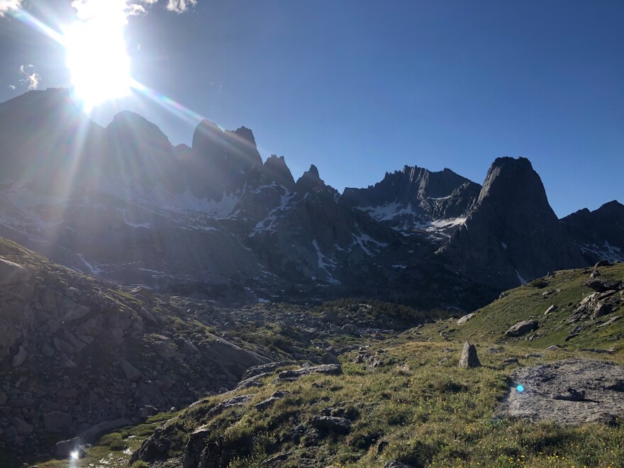  Big alpine mountains with green grass and boulders. 