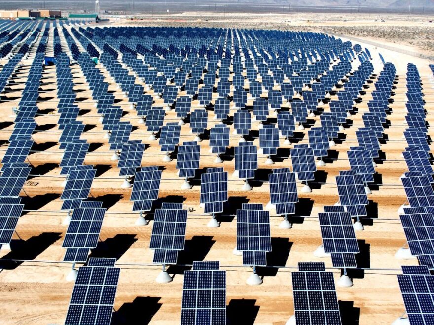 A series of rectangular solar panels, placed on a flat, arid landscape, each standing on its own short pedestal.