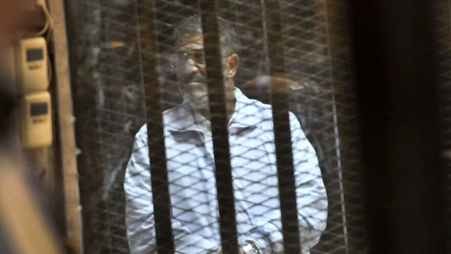 Egypt's ousted President Mohammed Morsi stands inside a glassed-in defendant's cage on Jan. 28 during his trial on charges related to the prison breaks at the height of the 18-day 2011 uprising against his predecessor Hosni Mubarak.