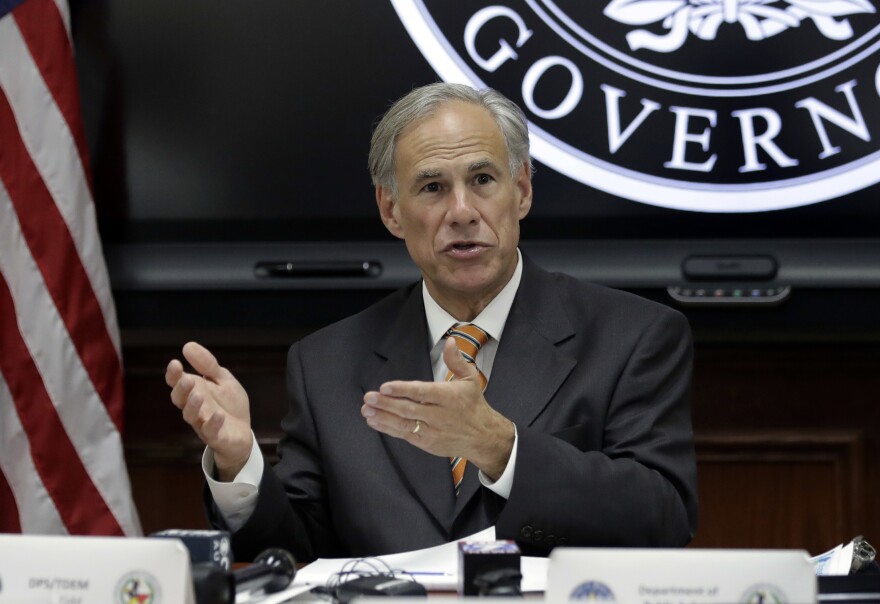 Abbott behind a table in front of the Texas seal.