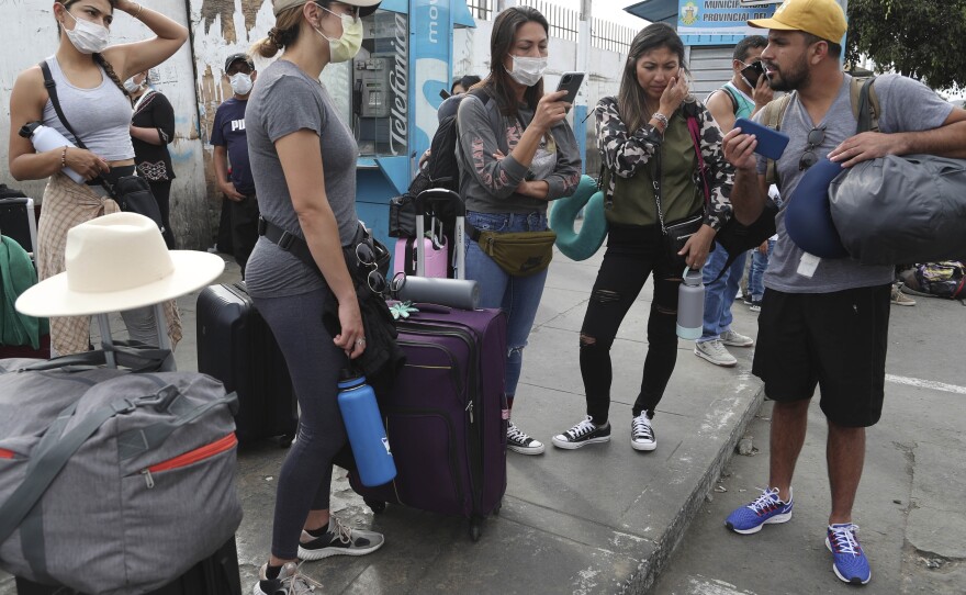 Tourists from the United States wait outside the closed Jorge Chavez International Airport for a member of the U.S. Embassy to escort them to a flight back to the U.S., in Callao, Peru, on March 20. It was the fifth day of a state of emergency decreed by Peru's government to prevent the spread of the new coronavirus.