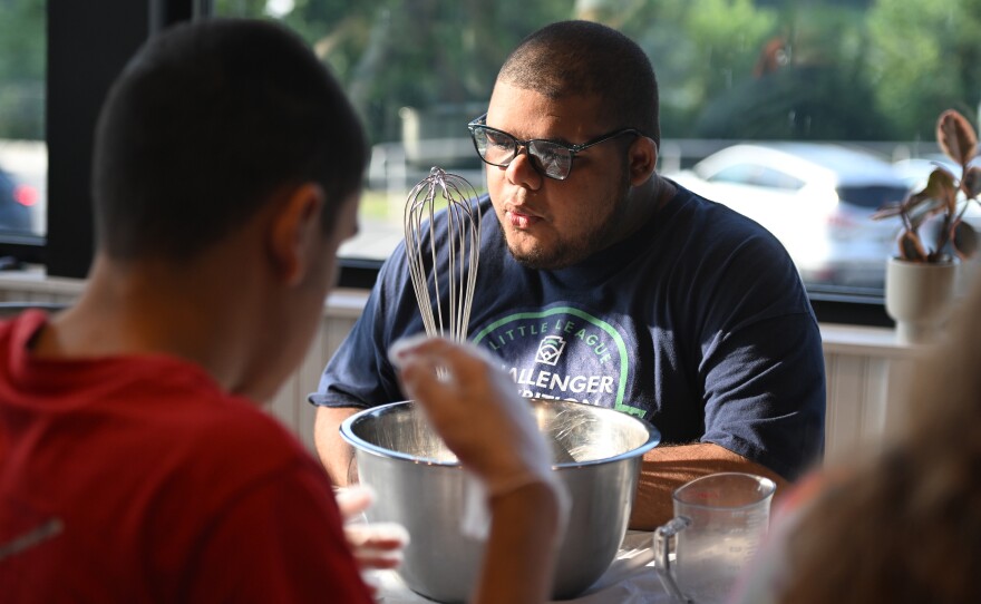 Ayden Thomas listens before whisking batter for pancakes.
