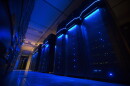 Rows of server banks glow blue inside an otherwise dark data center.