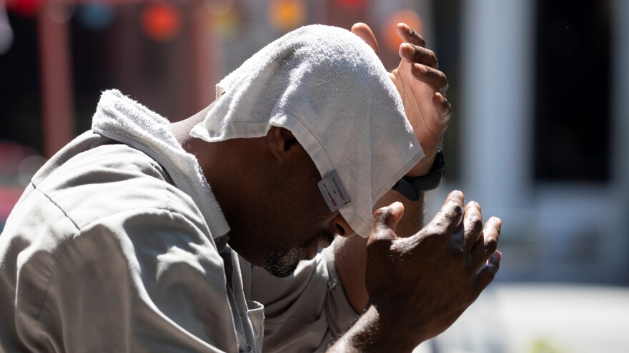 A man uses a wet towel to cool off.