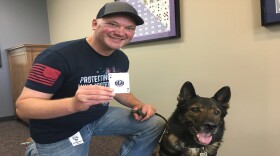 Jason Johnson holds up a playing card honoring his foundation Project K9 Hero. Axel is on the right.