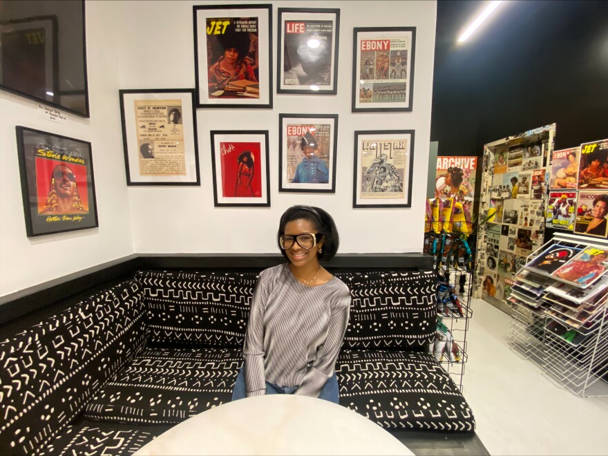 Archive CLT founder Cheryse Terry is seated in her shop and surrounded by various vintage magazine covers and concert posters on Dec. 21, 2022.