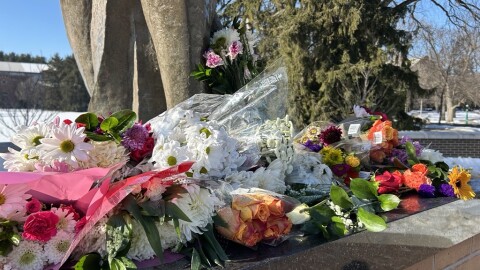 Flowers cover the base of the Spartan statue outside Spartan Stadium in honor of the 2023 campus shooting victims.